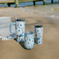 Mellow Monkey Ebb and Flow stainless steel wine tumblers with blue oyster shell pattern on a sandy beach.