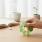 Mellow Monkey Ecto Cooler Feelzies sensory bracelet in translucent green with glitter on a wooden desk.