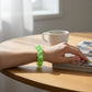 Mellow Monkey Ecto Cooler Feelzies Original Squishy sensory bracelet in bright green worn on a wrist at a desk.