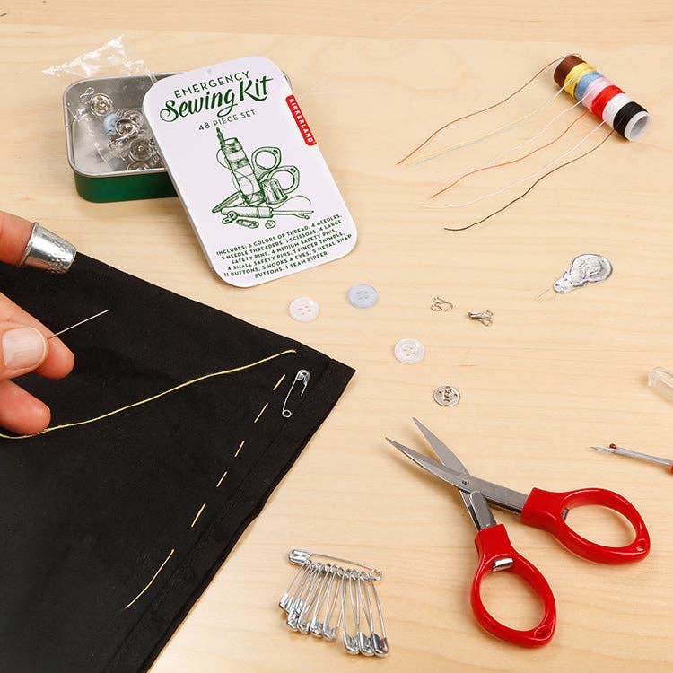 Mellow Monkey 48-piece emergency sewing kit with thread, scissors, needles, and buttons on a wooden surface.