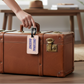 Mellow Monkey Emotional Baggage luggage tag in cream faux leather attached to a vintage brown suitcase handle
