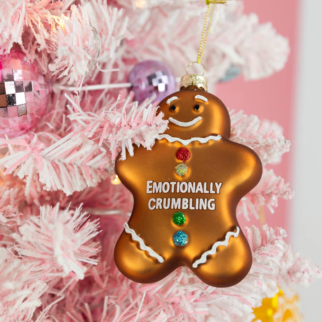 Mellow Monkey hand-blown glass gingerbread man ornament with Emotionally Crumbling text and colorful glitter buttons.