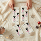 Mellow Monkey cozy crew socks in cream with an espresso martini print, held over a soft white faux fur blanket.