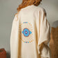 Mellow Monkey cream 4-layer muslin kimono robe with hand-painted blue and gold evil eye on back. One size.