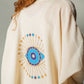 Mellow Monkey cream 4-layer muslin kimono robe with hand-painted blue and gold evil eye design on back.