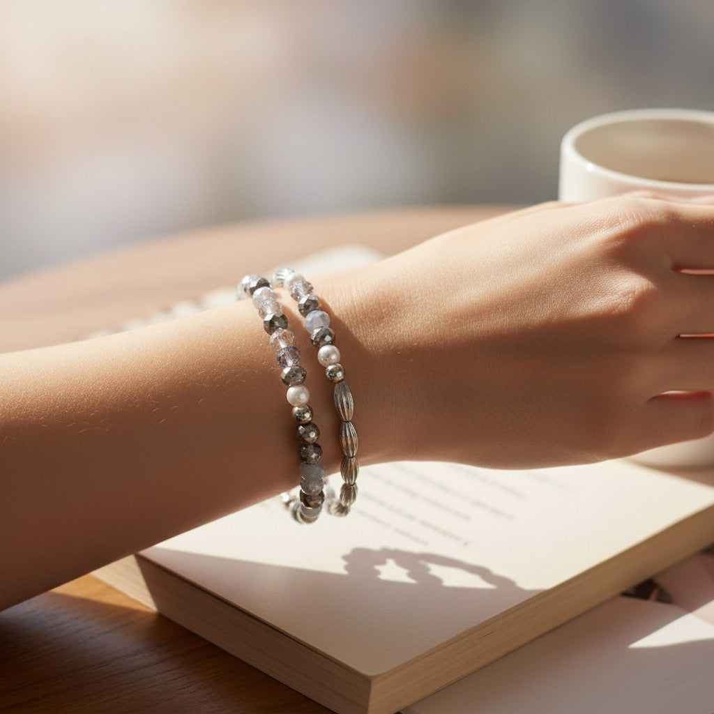 Mellow Monkey faceted gray and silver beaded bracelet worn on a wrist next to a book and coffee cup.