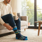 Mellow Monkey navy blue crew socks with I'm The Favorite Child text, worn by a man sitting on a sofa with a mug.