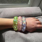 Mellow Monkey Feelzies sensory bracelets in lime, pink, and clear with glitter, worn on a wrist for stress relief.