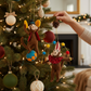 Mellow Monkey handcrafted felt circus monkey ornaments hanging on a decorated Christmas tree