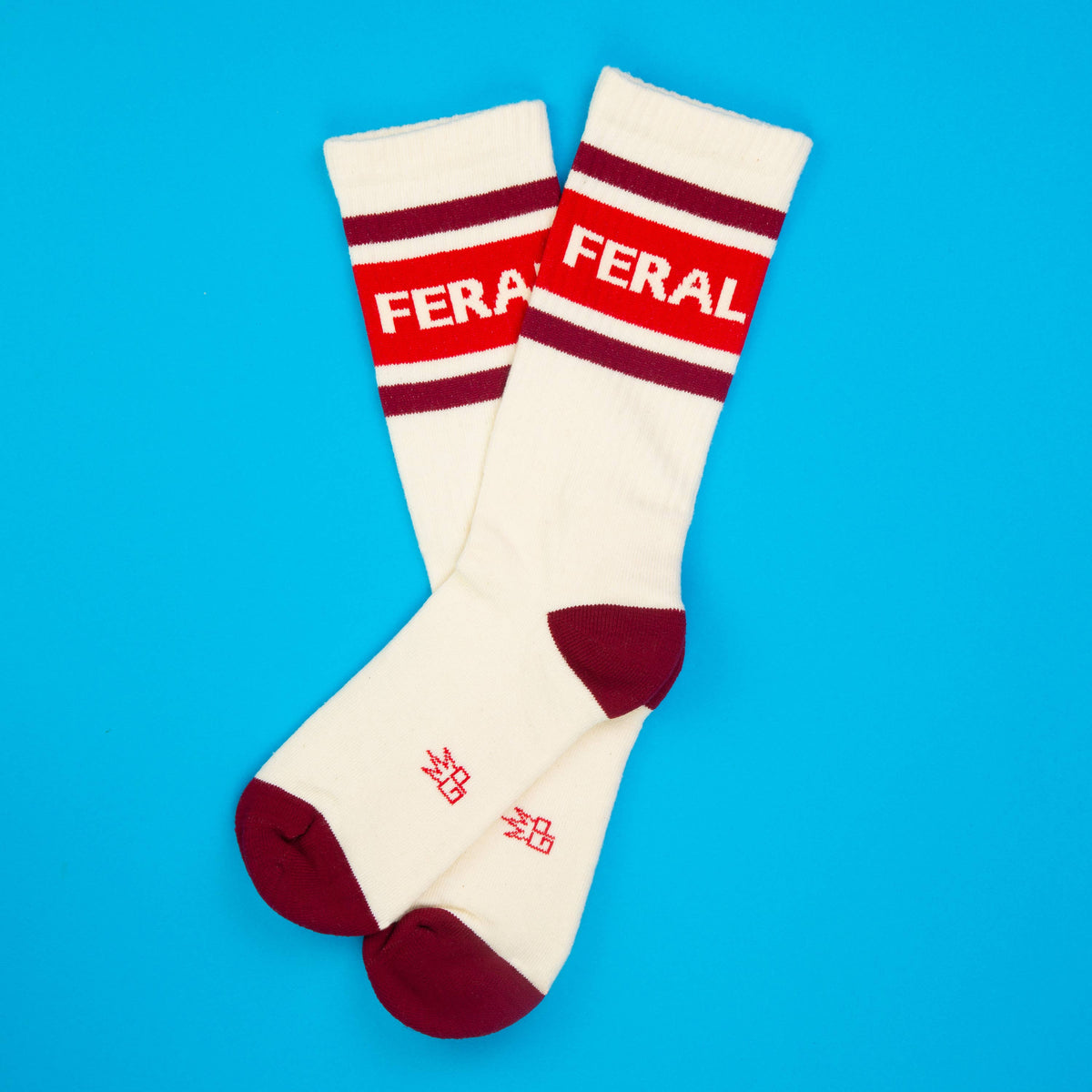 Mellow Monkey Feral gym crew socks in cream with maroon stripes and text on a bright blue background.