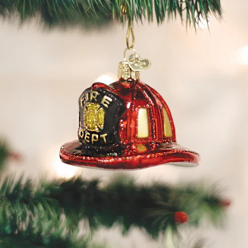 Mellow Monkey Old World Christmas blown glass fireman's helmet ornament, red with gold accents, hanging on a tree.