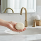 Mellow Monkey First Snowfall triple milled bar soap with snowflake embossing held under a gold bathroom faucet
