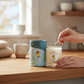 Mellow Monkey First Snowfall soy wax votive candle with Richard Scarry illustration packaging being lit on a table.
