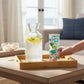 Mellow Monkey set of four 10-oz glass tumblers featuring colorful fish decals on a wooden tray with a water pitcher.