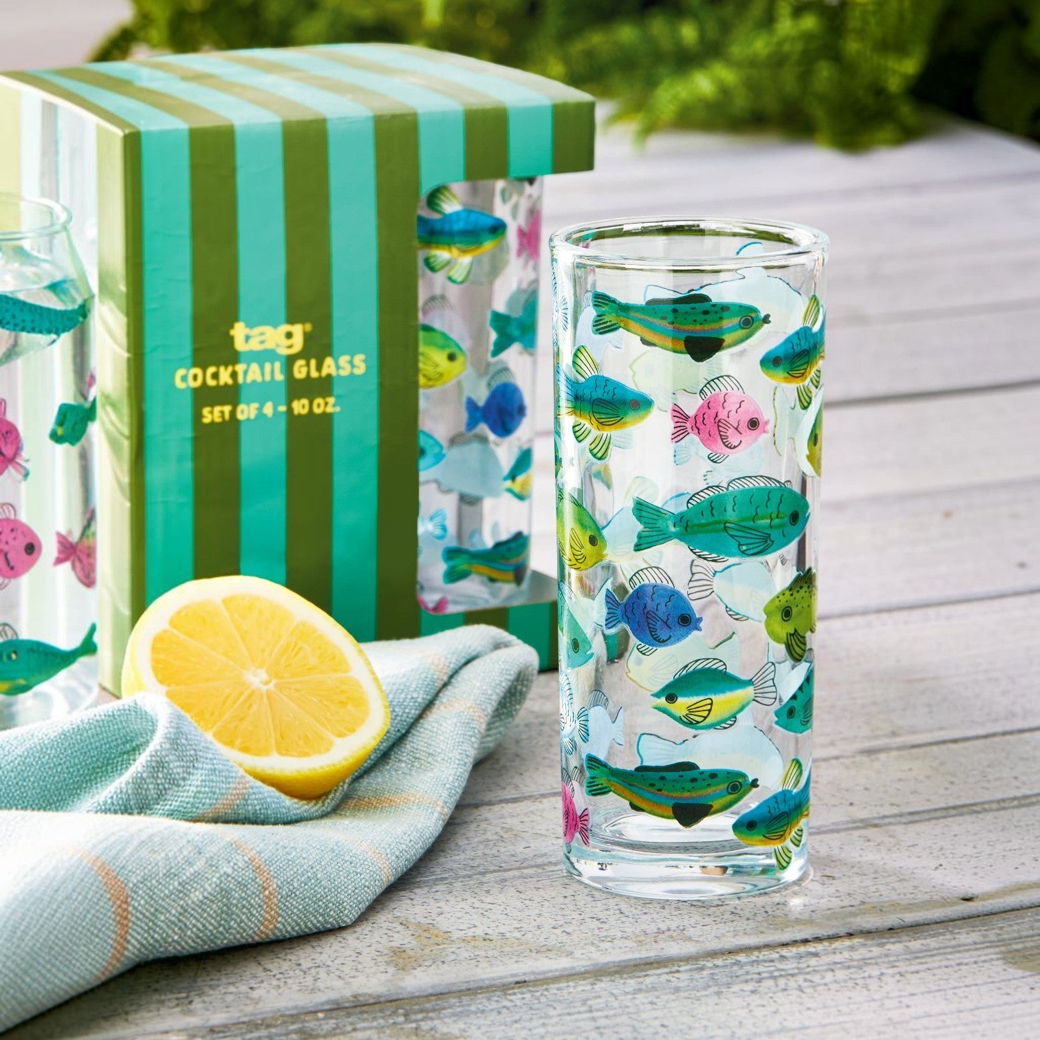 Mellow Monkey set of four 10-oz glass tumblers featuring colorful fish decals, displayed with lemon and napkin.