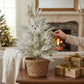 Mellow Monkey 25-inch flocked holiday spray with snow-covered pine needles in a woven basket on a wooden table