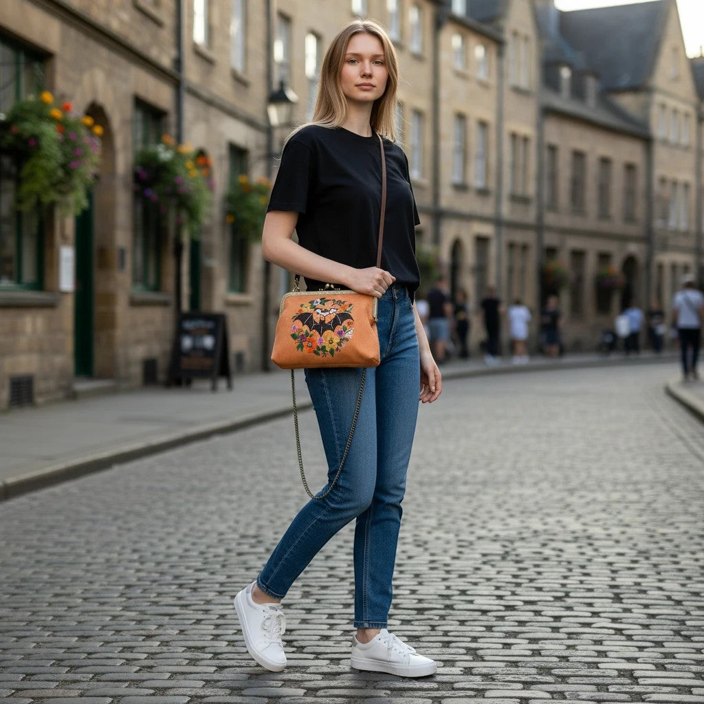 Model wearing a Mellow Monkey floral bat kiss lock bag in linen blend on a cobblestone street.