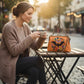Mellow Monkey linen blend handbag featuring an embroidered floral bat motif and vintage kiss lock frame on a cafe table