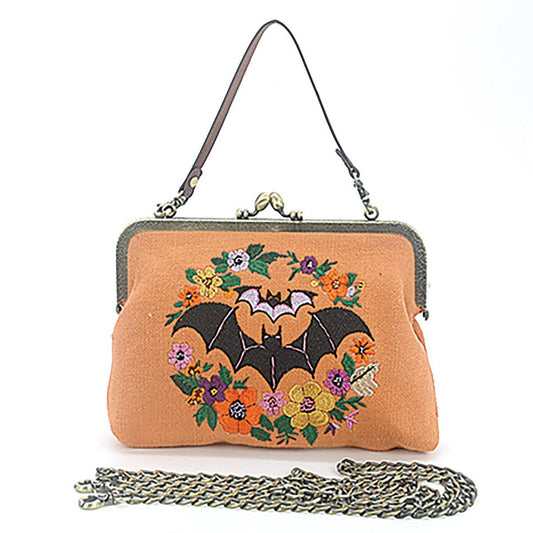 Mellow Monkey linen blend handbag featuring an embroidered bat and floral wreath with a vintage kiss lock clasp.