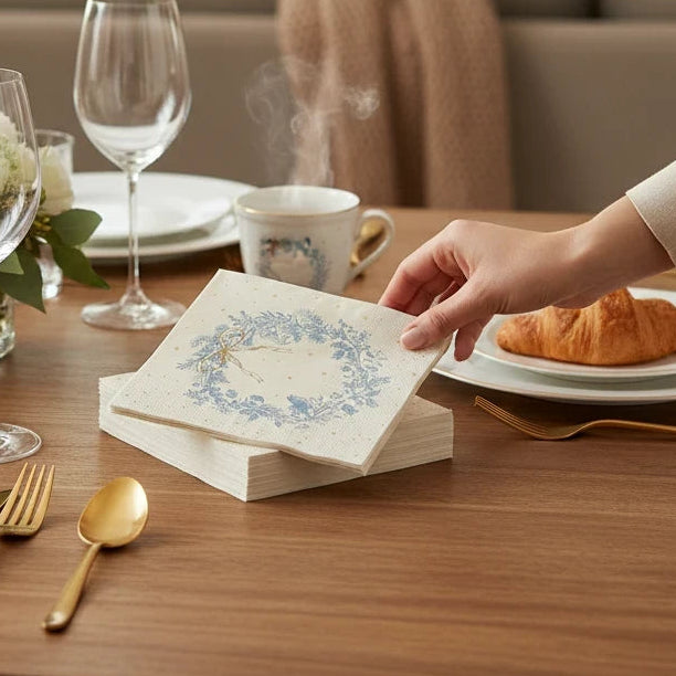 Mellow Monkey 3-ply paper cocktail napkins with a blue floral wreath design on a festive dining table setting