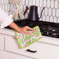 Mellow Monkey floral dish towel with pink flowers and green trim being used to wipe a kitchen counter.