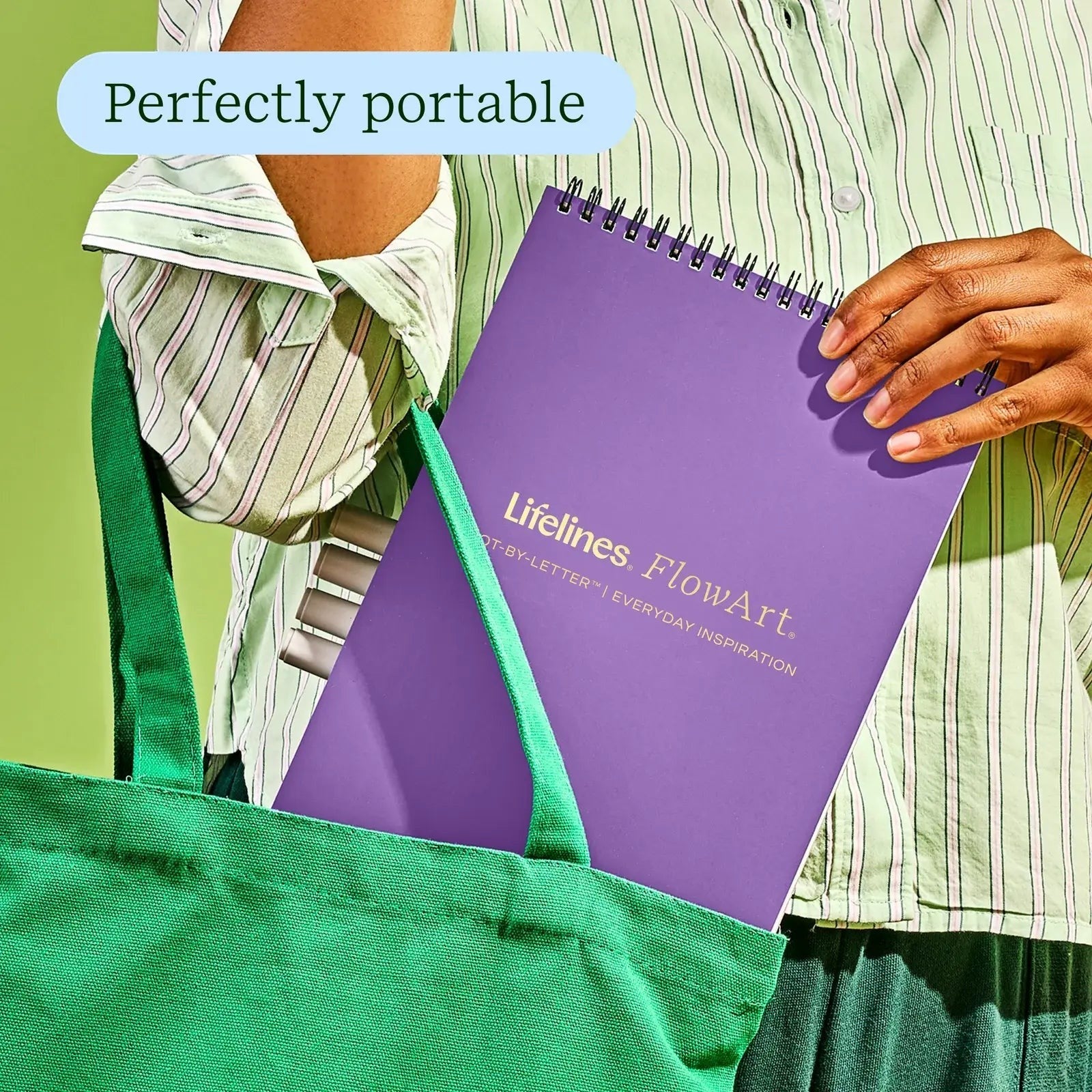 Mellow Monkey FlowArt dot-by-letter activity book with a purple cover being placed into a green tote bag.