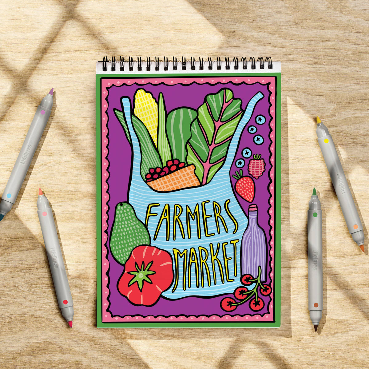 Mellow Monkey FlowArt coloring book featuring a Farmers Market scene with markers on a wooden table.