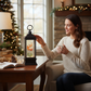 Mellow Monkey Flying Santa animated water lantern with swirling glitter on a wooden table next to a woman