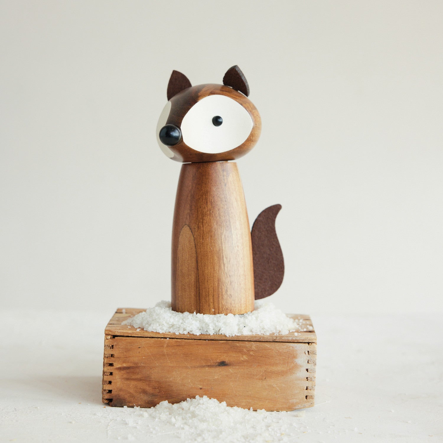 Mellow Monkey fox-shaped salt and pepper mill made of acacia wood with faux leather ears and tail on a wooden box.