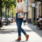 Woman wearing a Mellow Monkey Frankenstein and Bride vintage TV crossbody bag with a cream sweater and blue jeans.