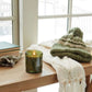 Mellow Monkey Thymes Frasier Fir candle in a green glass jar with pine needle embossing on a wooden table