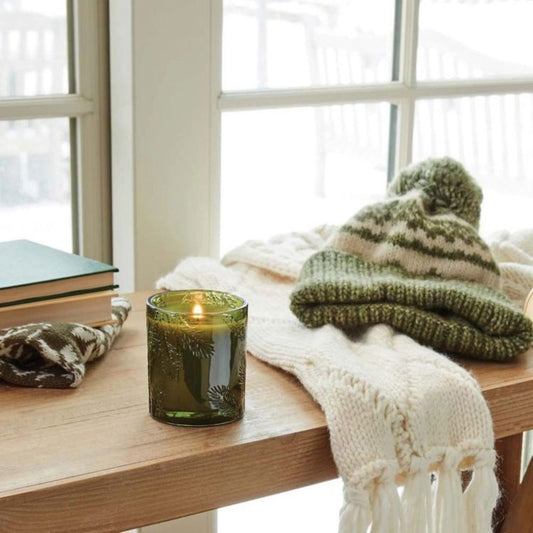 Mellow Monkey Thymes Frasier Fir candle in a green glass jar with pine needle embossing on a wooden table