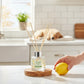Mellow Monkey Pet House reed diffuser in Fresh Citrus scent with a lemon on a wooden coaster in a bright kitchen.