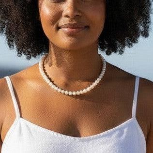 Mellow Monkey elegant white freshwater pearl strand necklace on a woman at the beach.