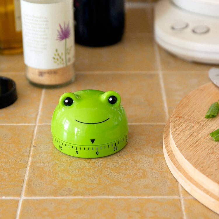 Mellow Monkey green frog-shaped mechanical kitchen timer made of ABS and steel on a tiled countertop
