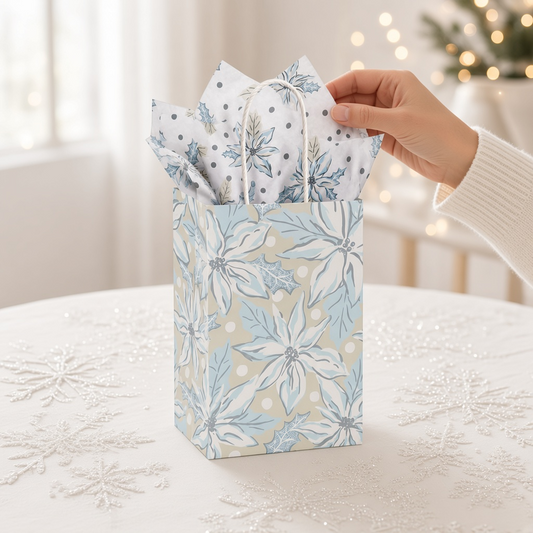 Mellow Monkey small frosted poinsettia gift bag with twisted paper handles and included tissue paper on a table.
