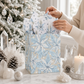 Mellow Monkey medium frosted poinsettia gift bag with blue floral print, twisted handles, and included tissue paper.