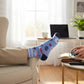Mellow Monkey light blue Funcle crew socks with pizza, dollar signs, and game icons worn by a person gaming.