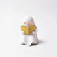 Mellow Monkey white ghost figurine reading a gold book with an LED tealight candle for whimsical bookshelf decor.