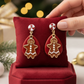 Mellow Monkey handmade gingerbread drop earrings with surgical steel wires on a red velvet display cushion.