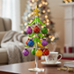 Mellow Monkey 12-inch glass Christmas tree with colorful quilted ornaments and a gold star topper on a wooden table.