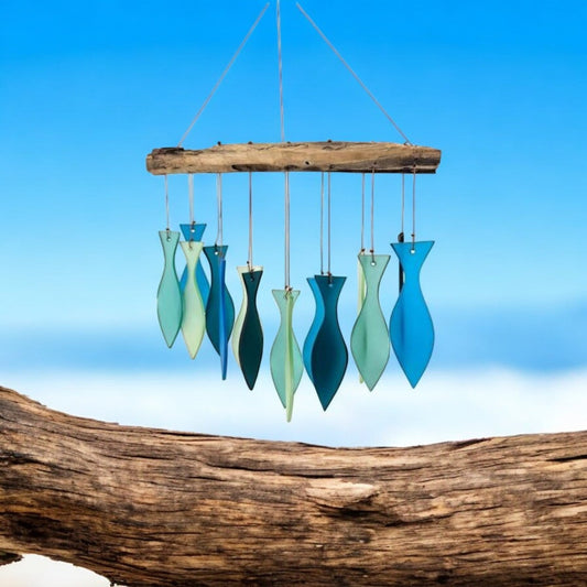 Mellow Monkey handcrafted wind chime featuring blue and green sandblasted glass fish hanging from a driftwood branch.