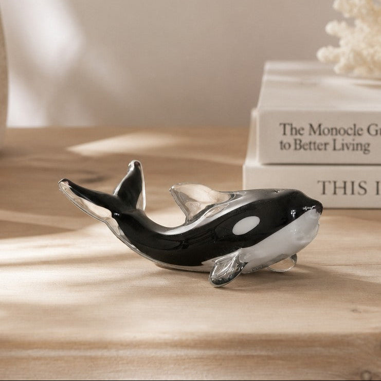 Mellow Monkey 5-inch glass killer whale figurine in black and white, displayed on a wooden table with coastal decor.