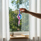 Mellow Monkey 9-inch hand-blown glass spiral ornament with blue and purple swirls hanging in a sunlit window