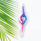 Mellow Monkey 9-inch hand-blown glass spiral ornament with swirling blue, pink, and white colors next to a palm leaf.