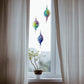 Mellow Monkey hand-blown glass spiral ornaments in vibrant colors hanging in a window to catch the light.