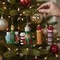 Mellow Monkey glass thermos ornaments with glitter, featuring vintage-inspired plaid and geometric patterns on a tree.