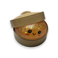 Mellow Monkey rainbow glitter mystery dumpling squeeze toy with a cute face inside a plastic steamer basket container.