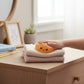 Mellow Monkey orange glitter dumpling squeeze toy with a cute face being pressed by a hand on a wooden desk.