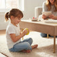 A young girl sitting on a rug playing with a yellow Mellow Monkey Orbee glitter dumpling stress relief fidget toy.